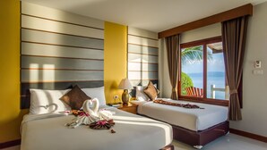 Habitación de hotel con dos camas, vista al mar y una ventana con cortinas.