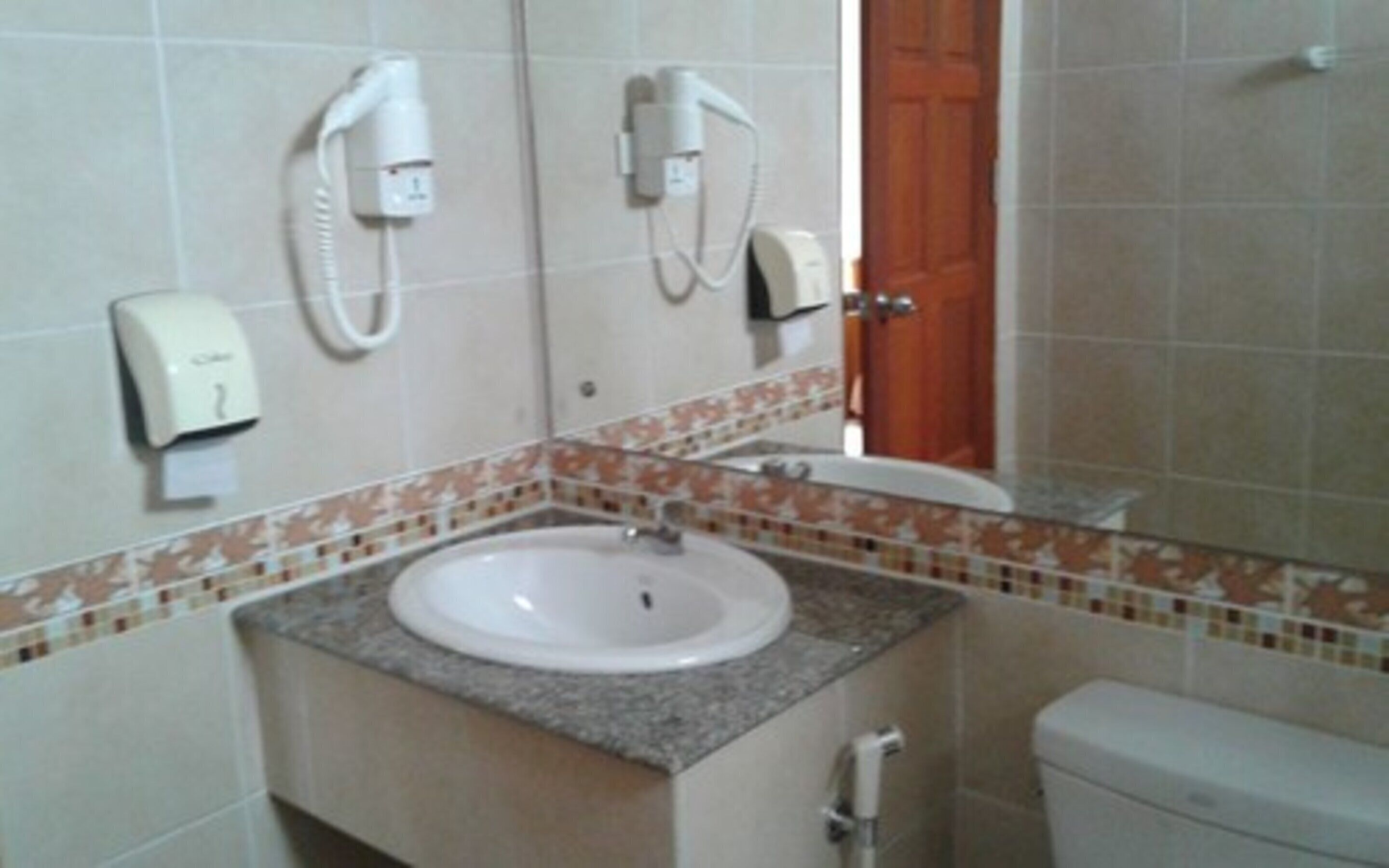 A bathroom with a sink, a toilet, and a shower. There are two hand dryers mounted on the wall.