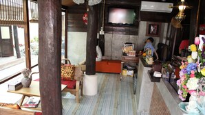 A traditional interior with wooden furniture, a television, and a variety of decorative items. - PJ House (Chiang Mai)