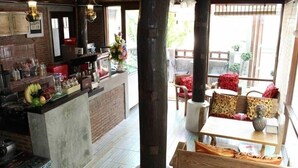 A cozy restaurant with a central bar, wooden furniture, and a view of the outdoors. - PJ House (Chiang Mai)