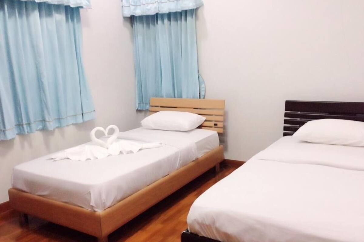 A hotel room with two beds, light blue curtains, wooden headboards, and white bedding.