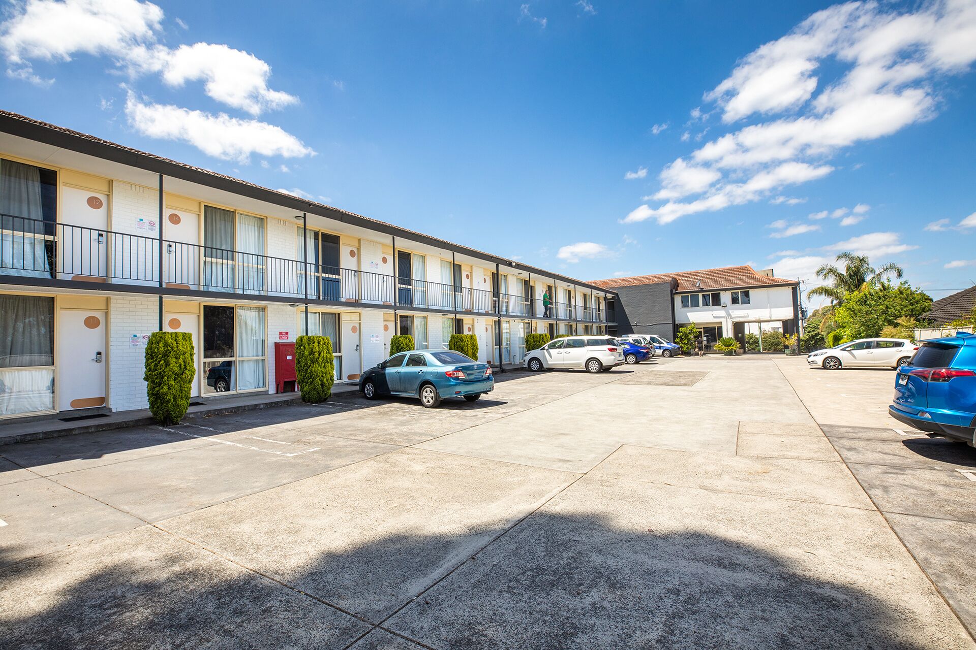 A motel with multiple rooms, a parking lot, and a building with a tiled roof.
