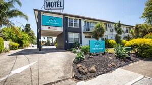 Motel llamado 'The Mulgrave Motel' con un letrero, una entrada de vehículos y un jardín ajardinado con rocas y plantas.