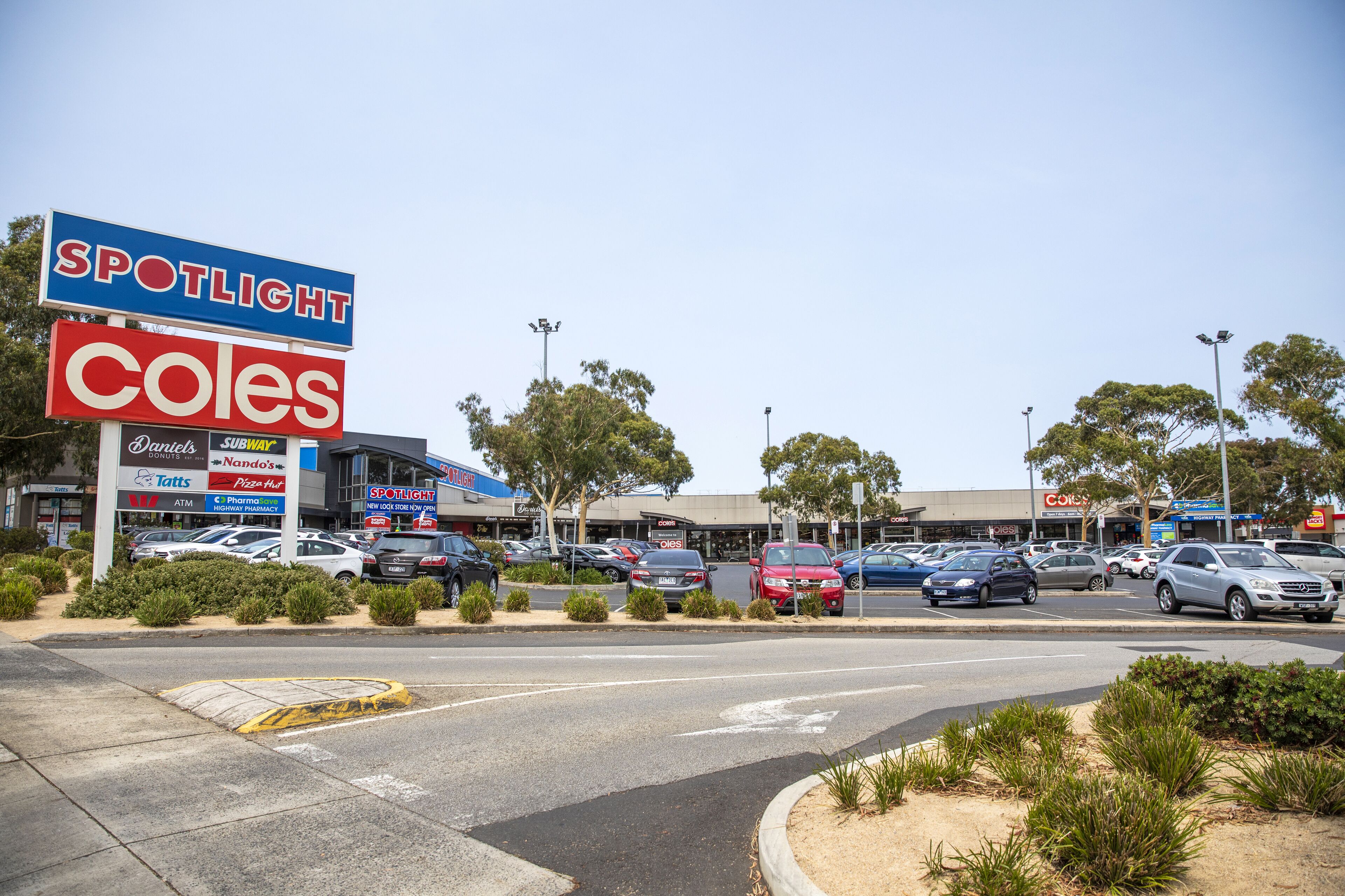 A parking lot with multiple cars and a large sign for a supermarket.