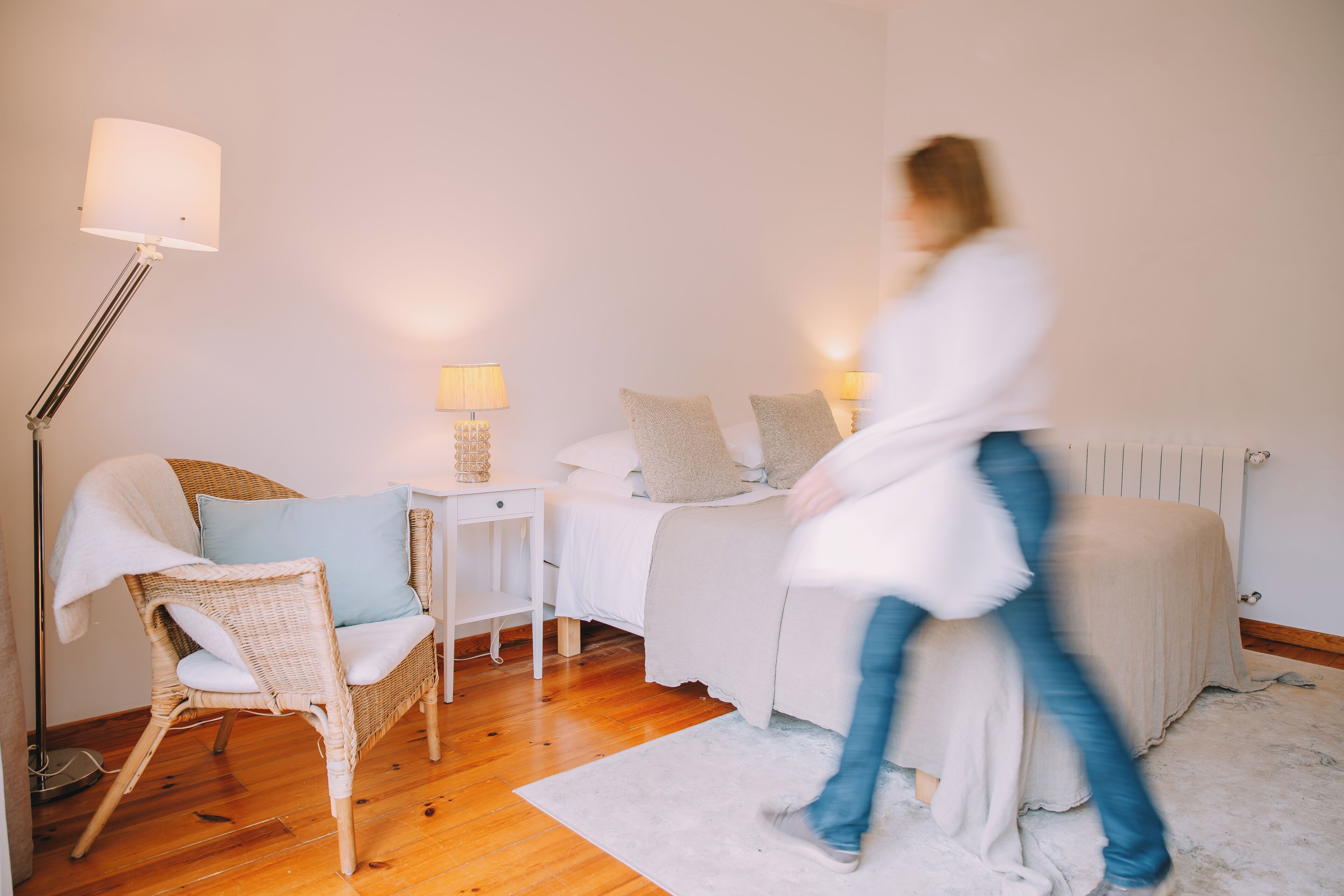 A bedroom with a bed, bedside tables, a lamp, a chair, and a radiator.