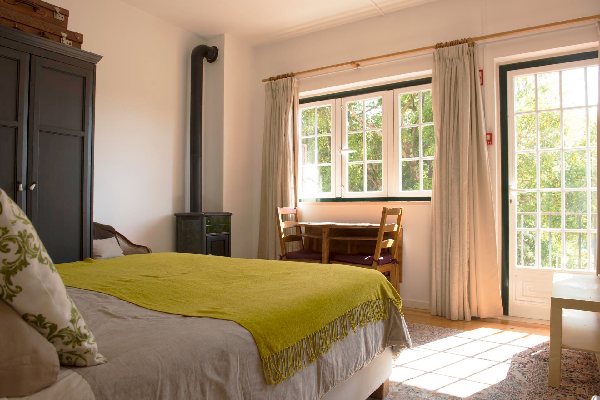 Ein Schlafzimmer mit einem Bett, einem Holztisch und einem Fenster mit Vorhängen.
