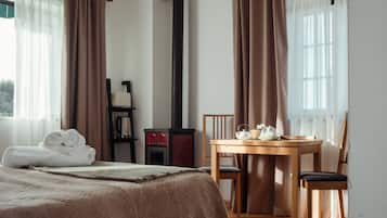A hotel room with a bed, a table with chairs, a fireplace, and curtains.