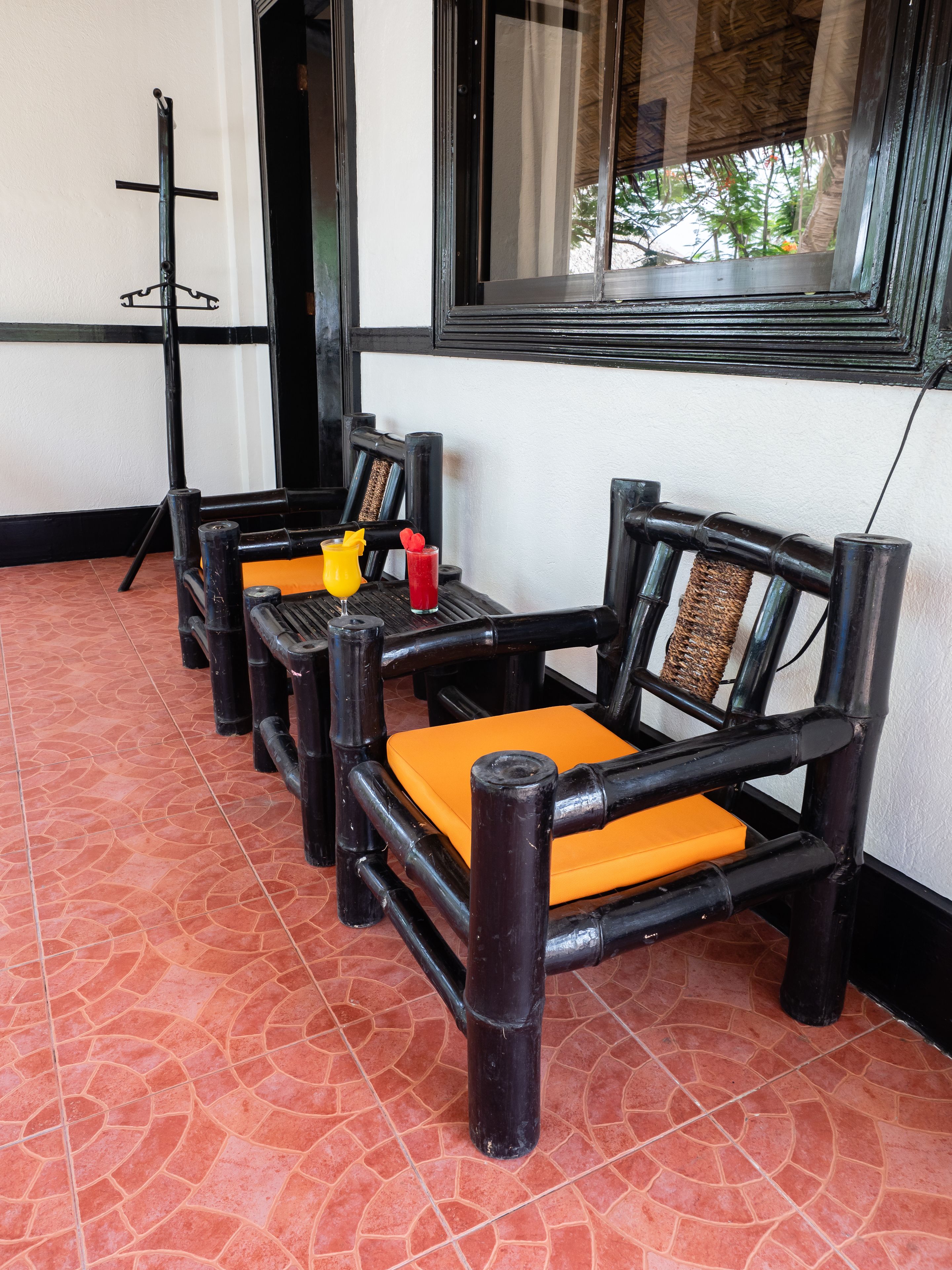 A row of black wooden chairs with orange cushions and a black metal stand.