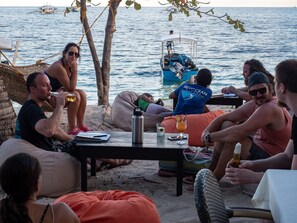 A group of people relaxing on a sandy beach with a view of the sea and boats.