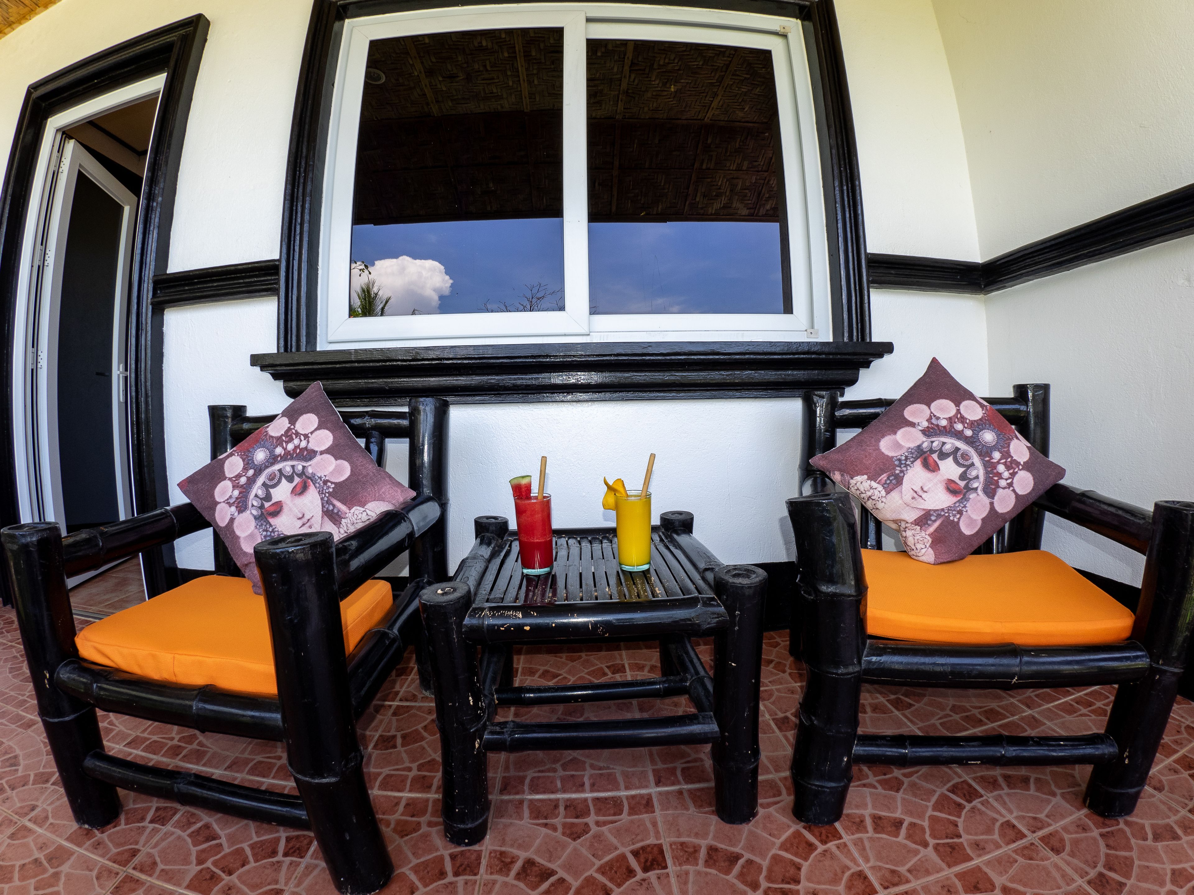 A seating area with two chairs and a table, a window with a view of the sky, and a door.