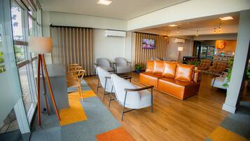 A hotel lobby with a sofa, chairs, a TV, and a refrigerator.