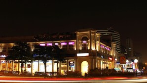 Un hotel de varios pisos con señalización iluminada, un paso de peatones y una calle con estelas de luz.