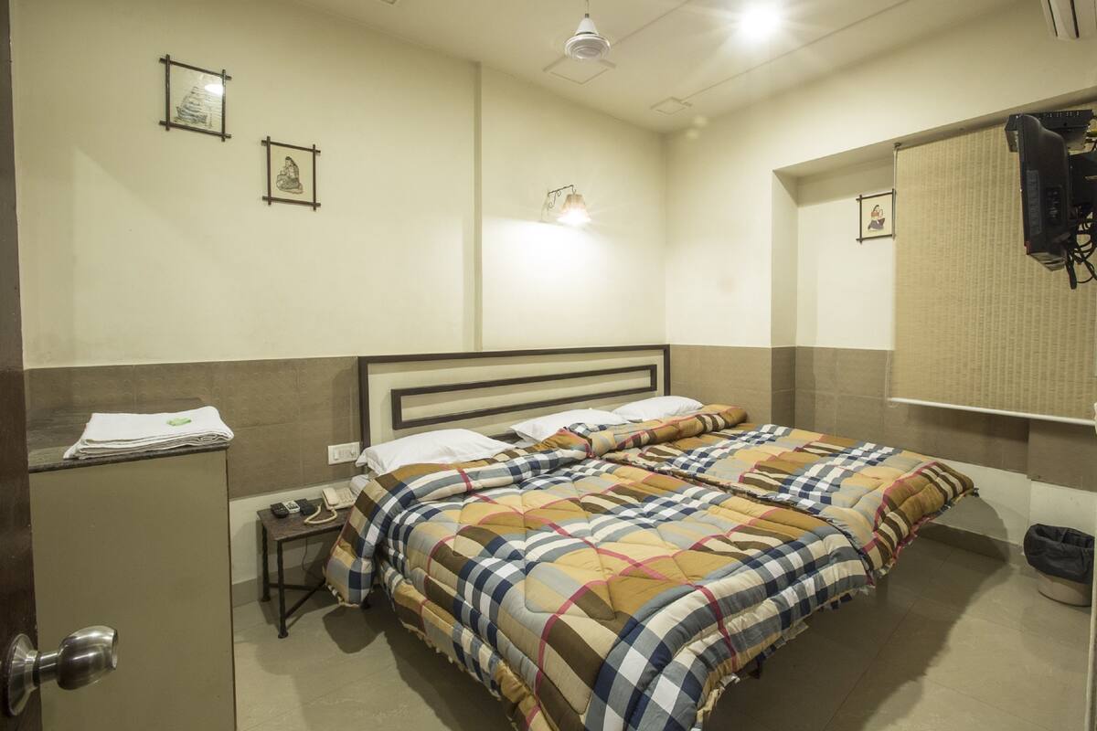 A hotel room with a double bed, a bedside table with a lamp, a mirror, and a wardrobe.