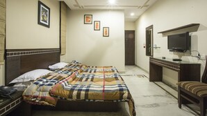 Habitación de hotel con cama, mesita de noche, televisor y escritorio con silla.