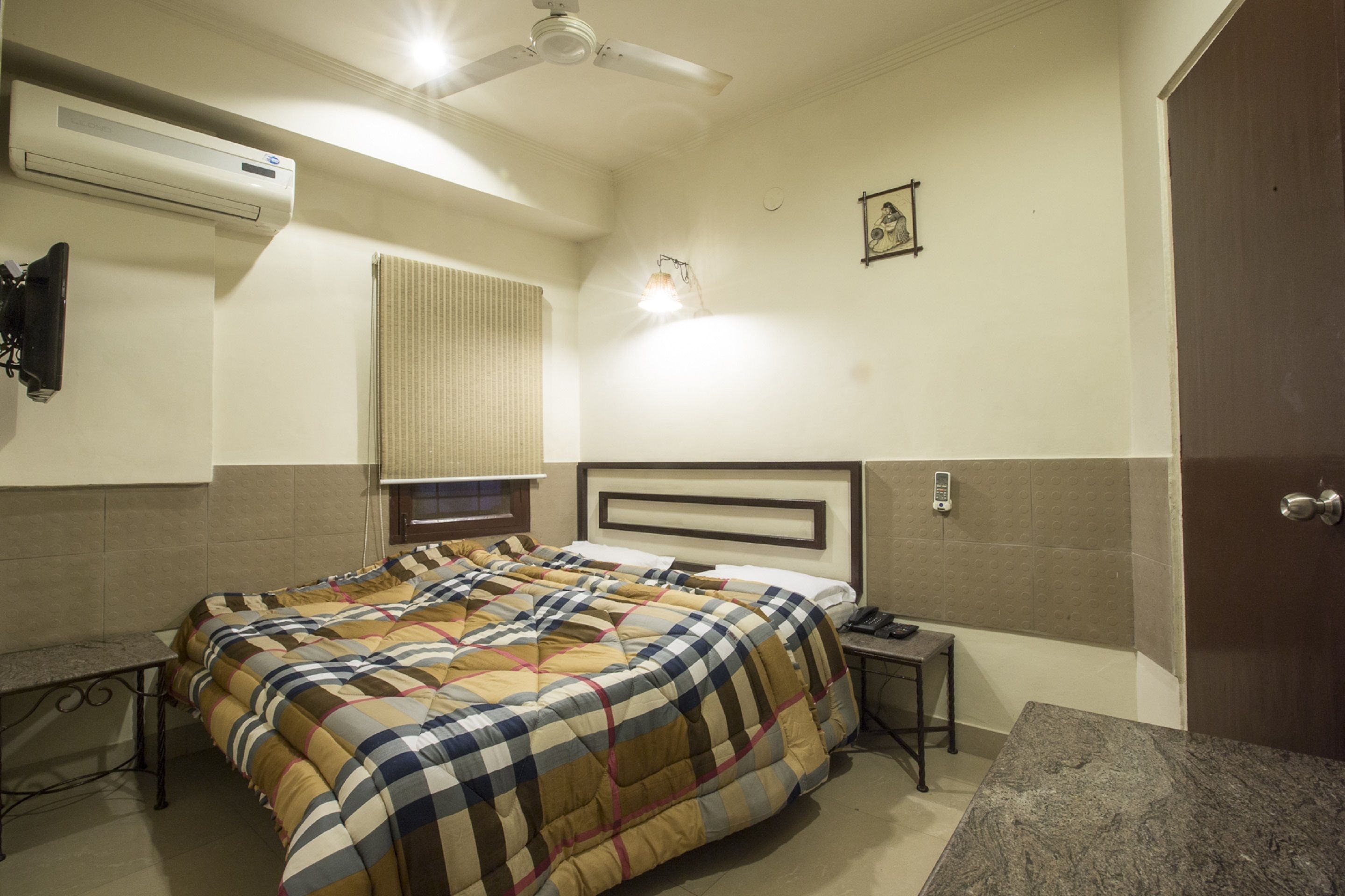 A hotel room with a bed, bedside table, nightstand, and a ceiling fan.