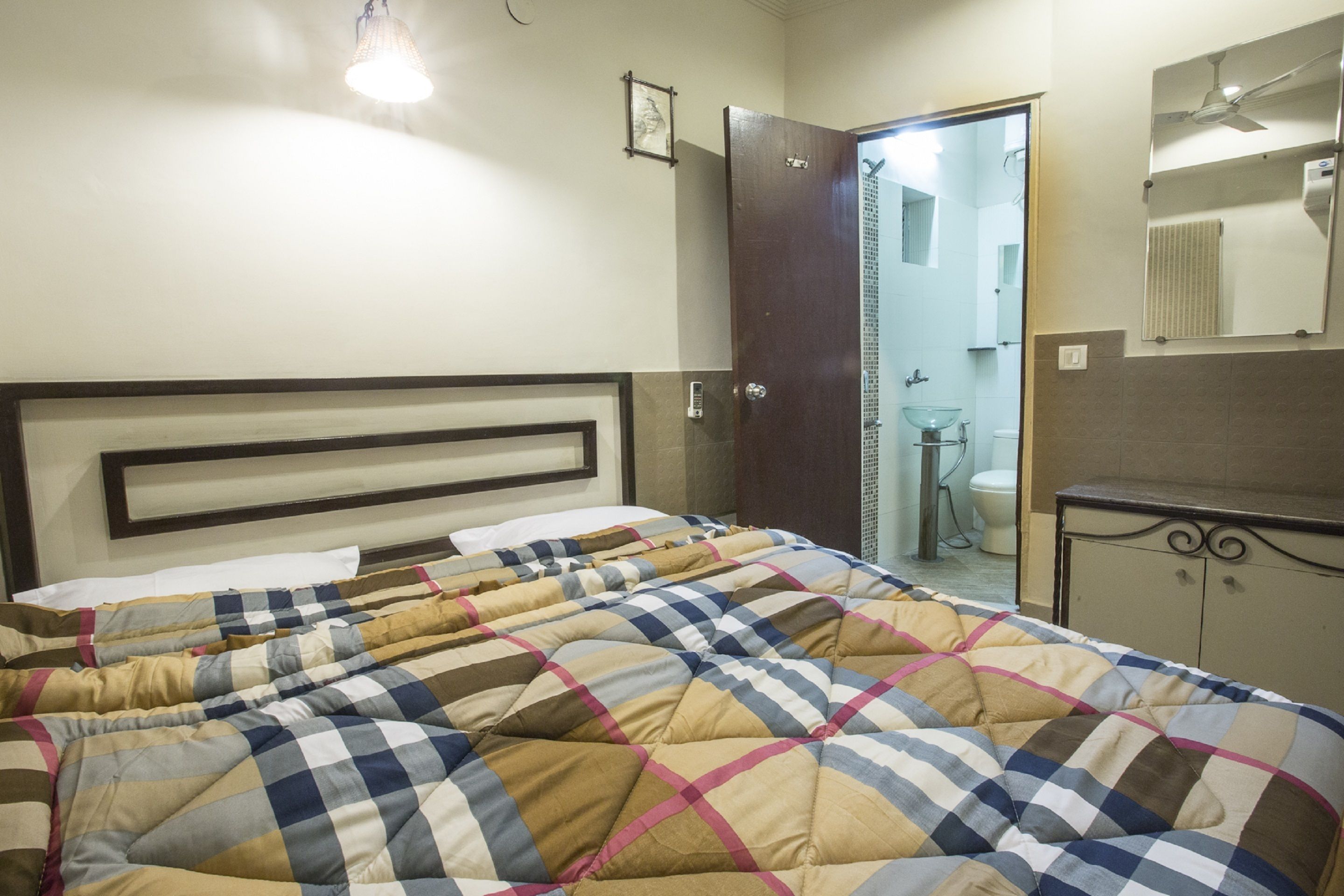 Un dormitorio con una cama, una puerta al baño y un espejo en la pared.