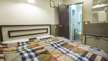 Un dormitorio con una cama, una puerta al baño y un espejo en la pared.