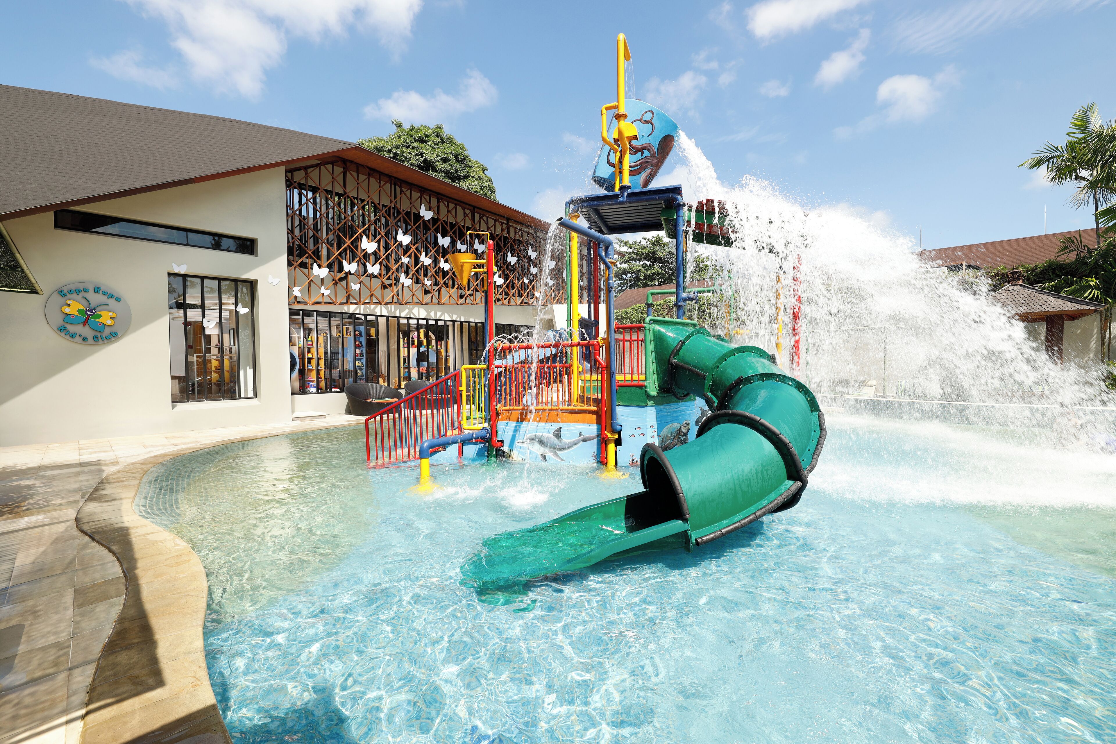 Un parco acquatico con uno scivolo verde e una fontana d'acqua.