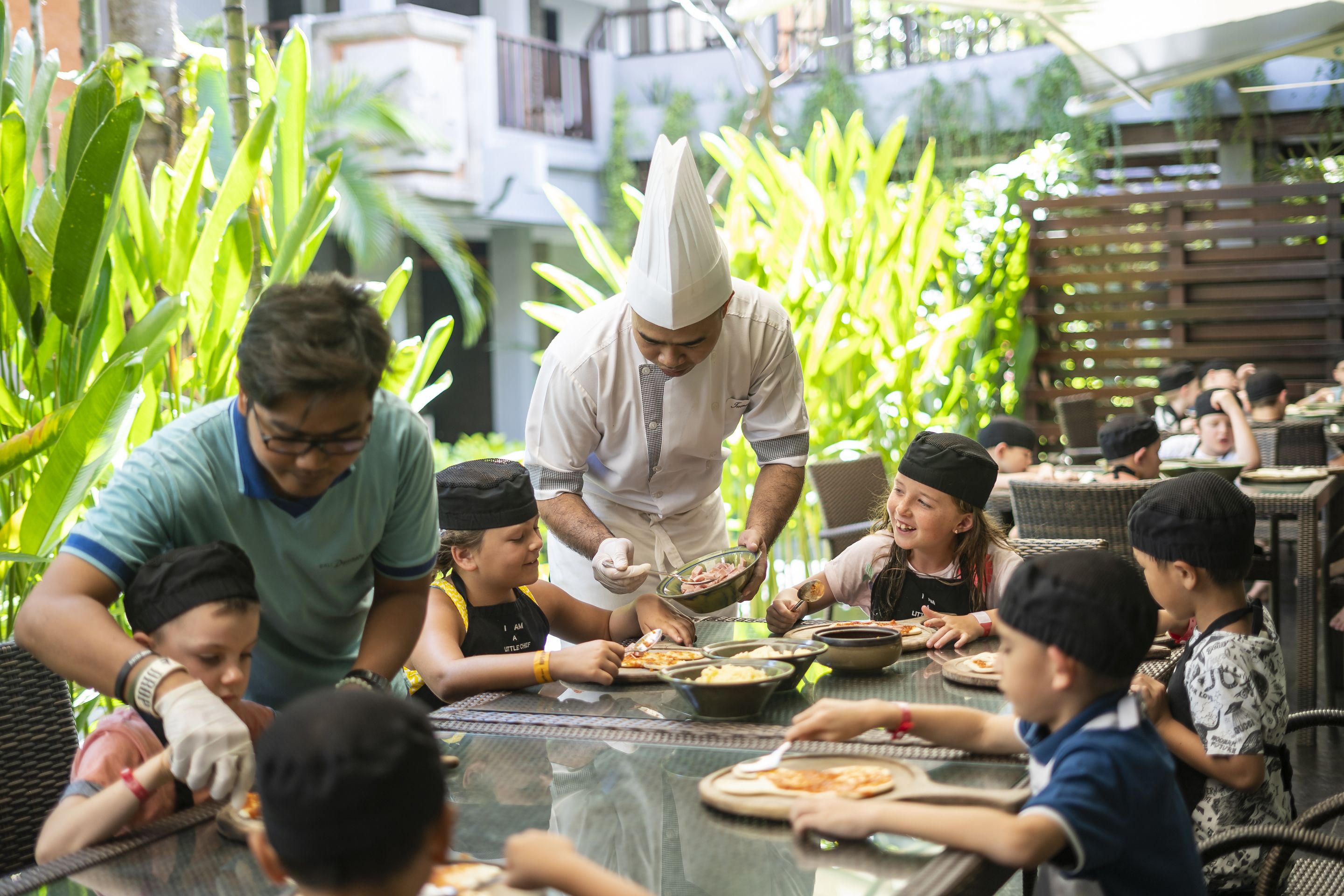 A group of people dining outdoors with a chef serving food.