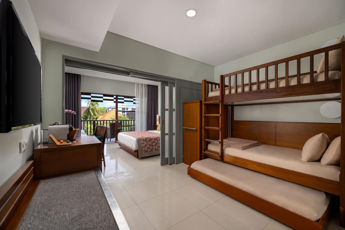 Een hotelkamer met een stapelbed, een bureau met stoel, een televisie en een balkon met uitzicht.