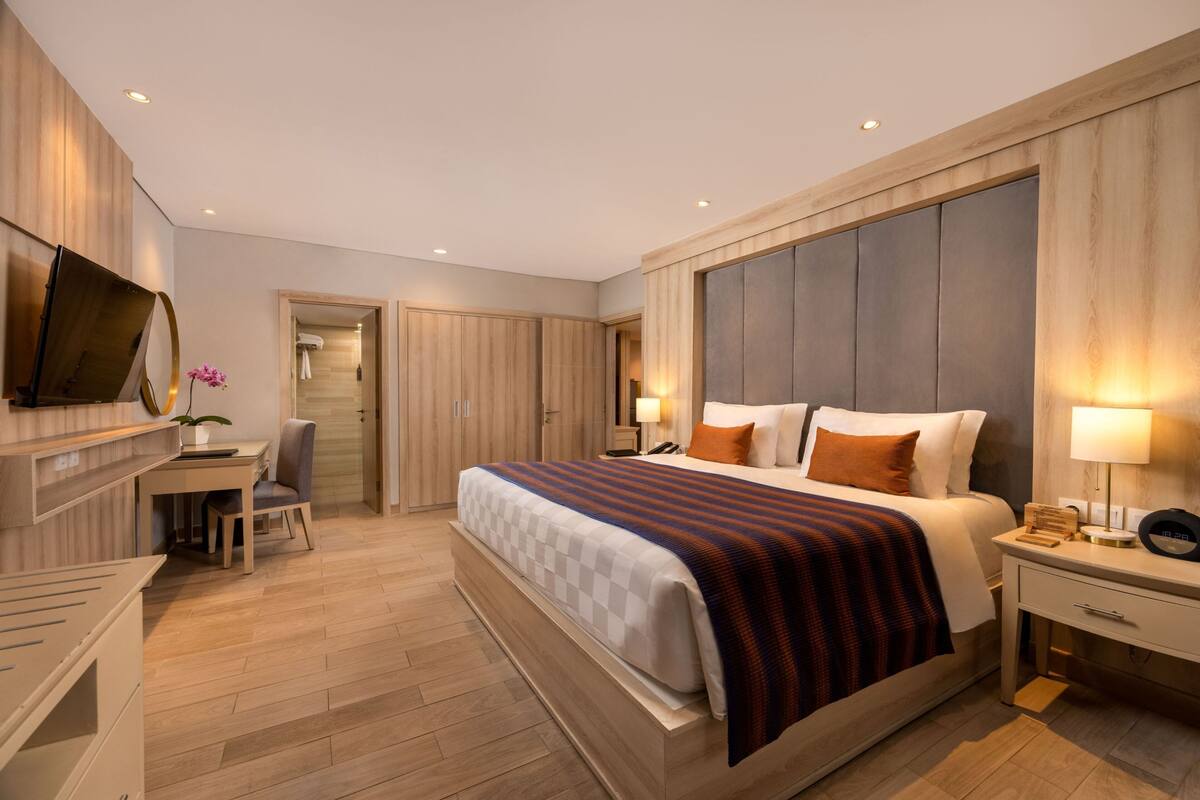 Een moderne hotelkamer met een groot bed, nachtkastjes, een bureau en een televisie.