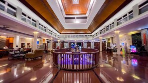A spacious lobby with a central circular seating area, high ceilings with wooden paneling, and a modern design. - Bali Dynasty Resort (Kuta)