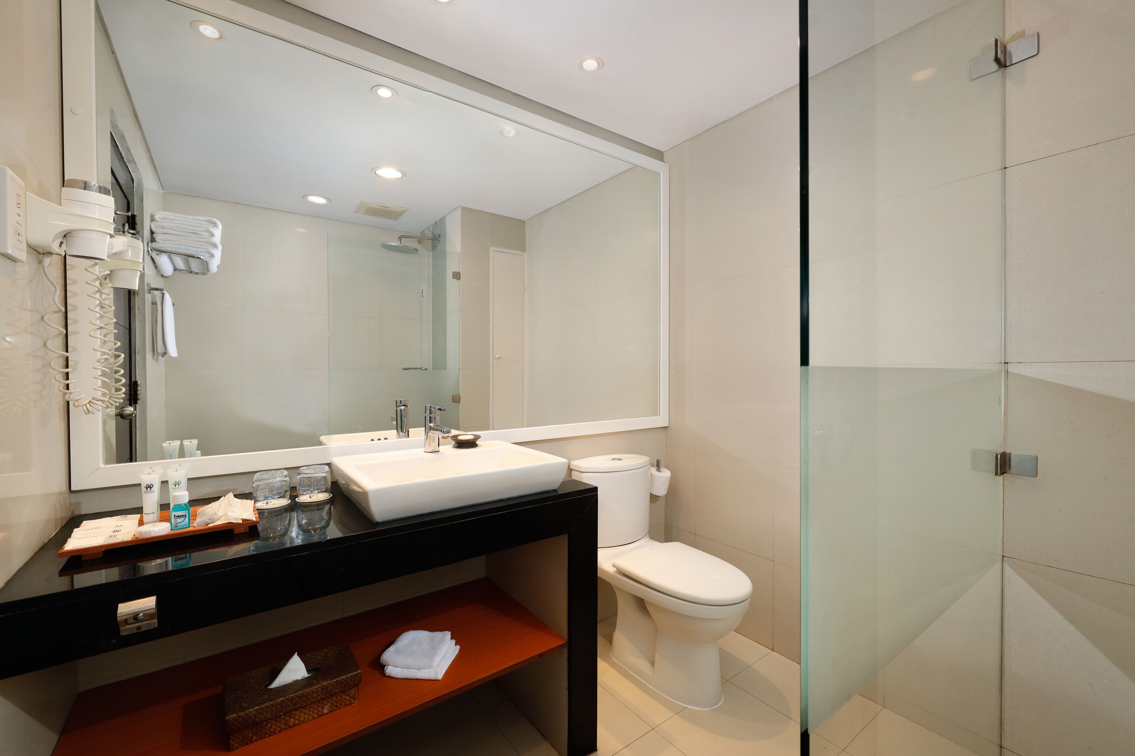 A modern bathroom with a large mirror, white sink, and glass shower enclosure.
