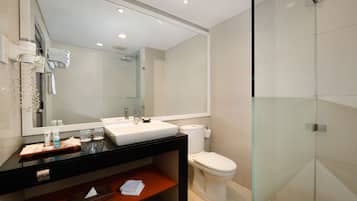 A modern bathroom with a large mirror, white sink, and glass shower enclosure.