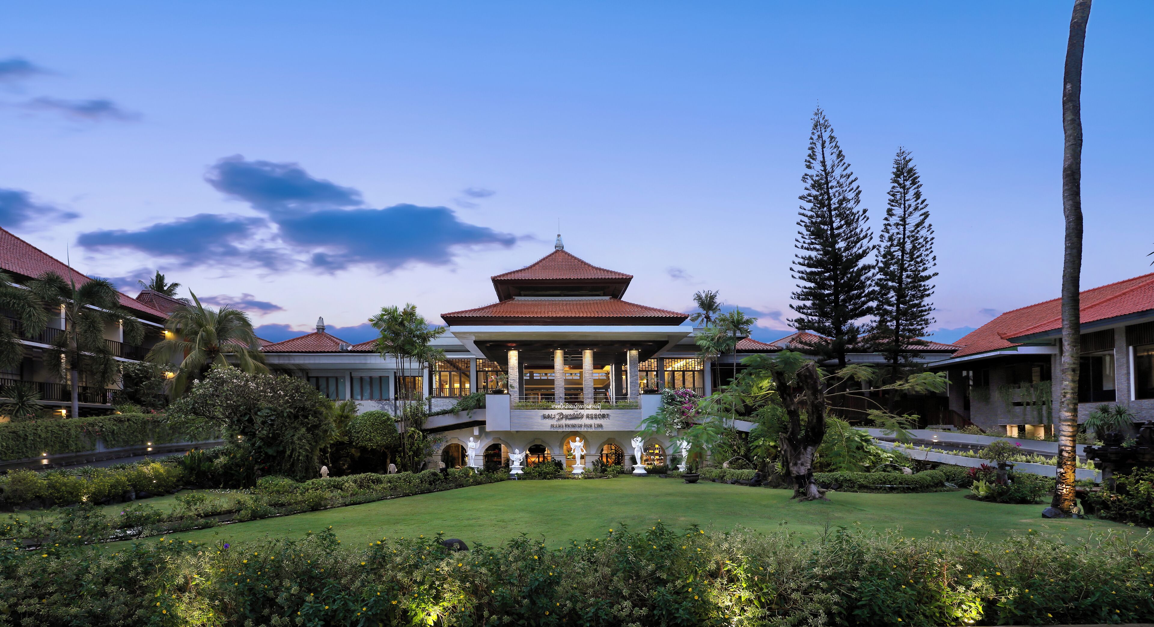A hotel with a traditional pagoda-style building, lush gardens, and a well-maintained lawn.