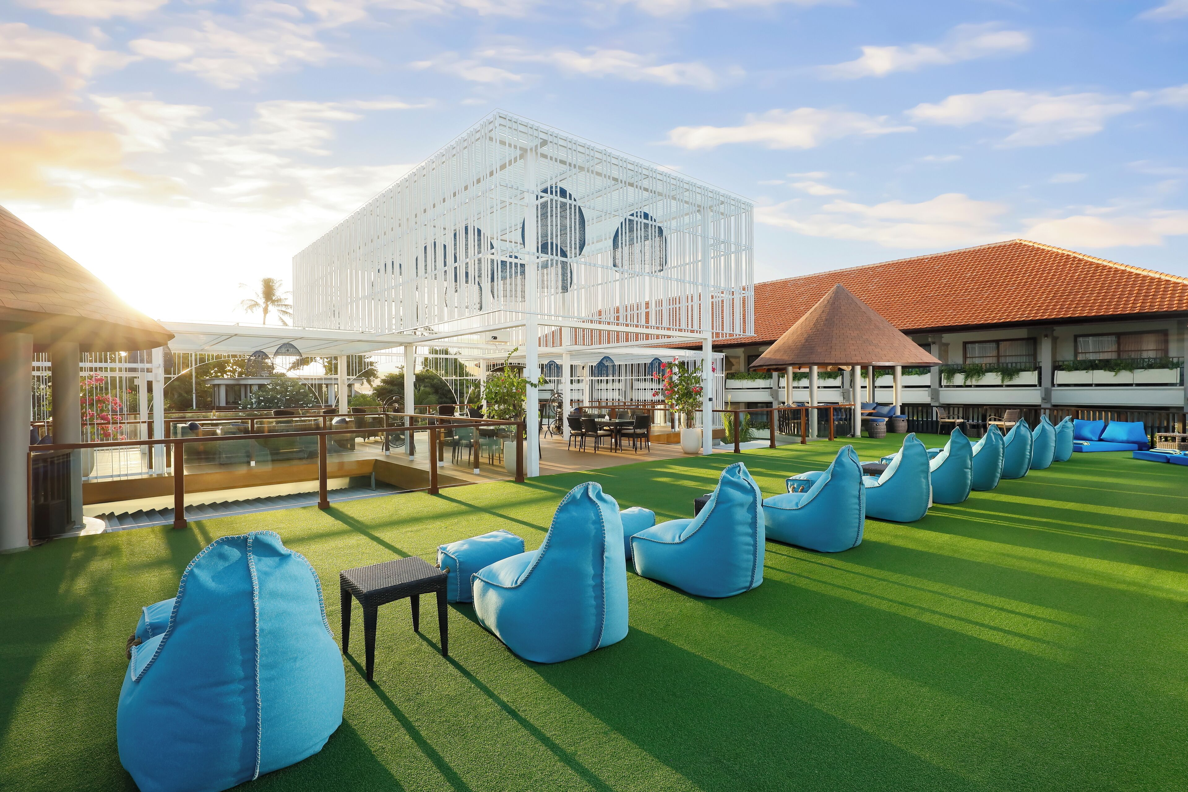 Une terrasse sur le toit, dotée d’un revêtement d’herbe artificielle, de fauteuils en forme de haricots bleus et d’une structure blanche agrémentée de fenêtres rondes.