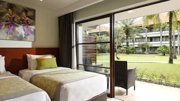 A hotel room with two beds, a large window, and a view of a courtyard with palm trees.