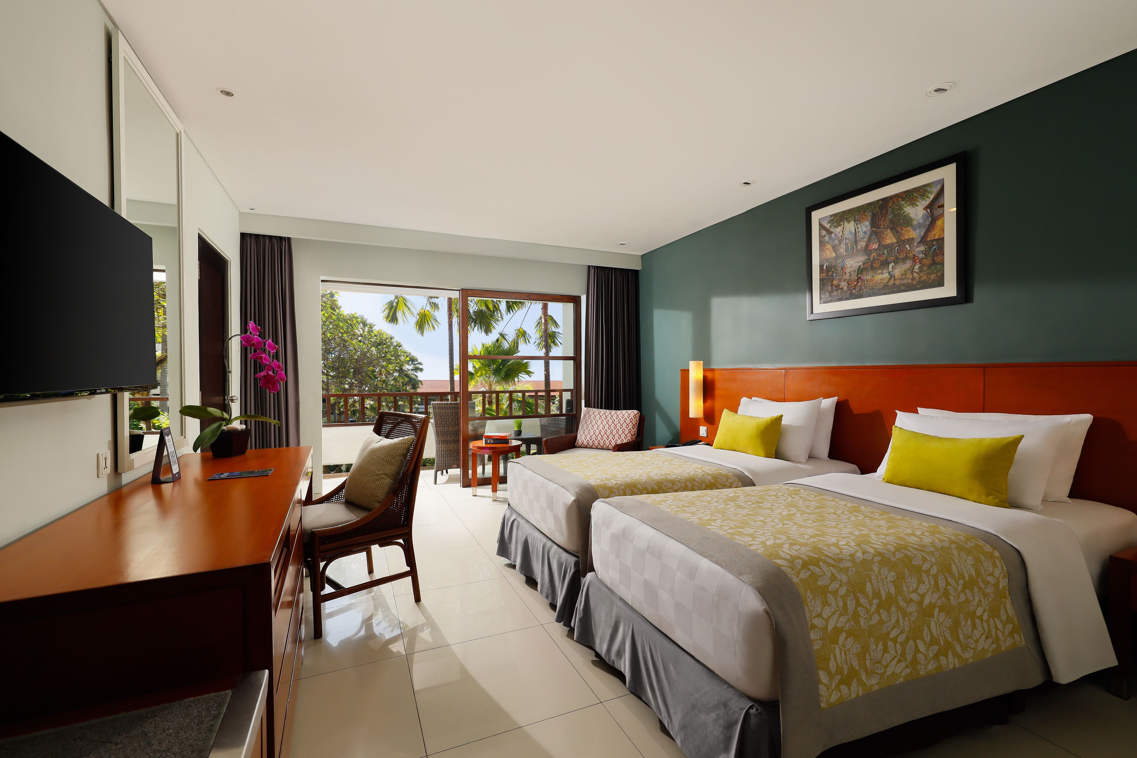Habitación de hotel con dos camas, un escritorio, una silla, un televisor y un balcón con vistas a palmeras.