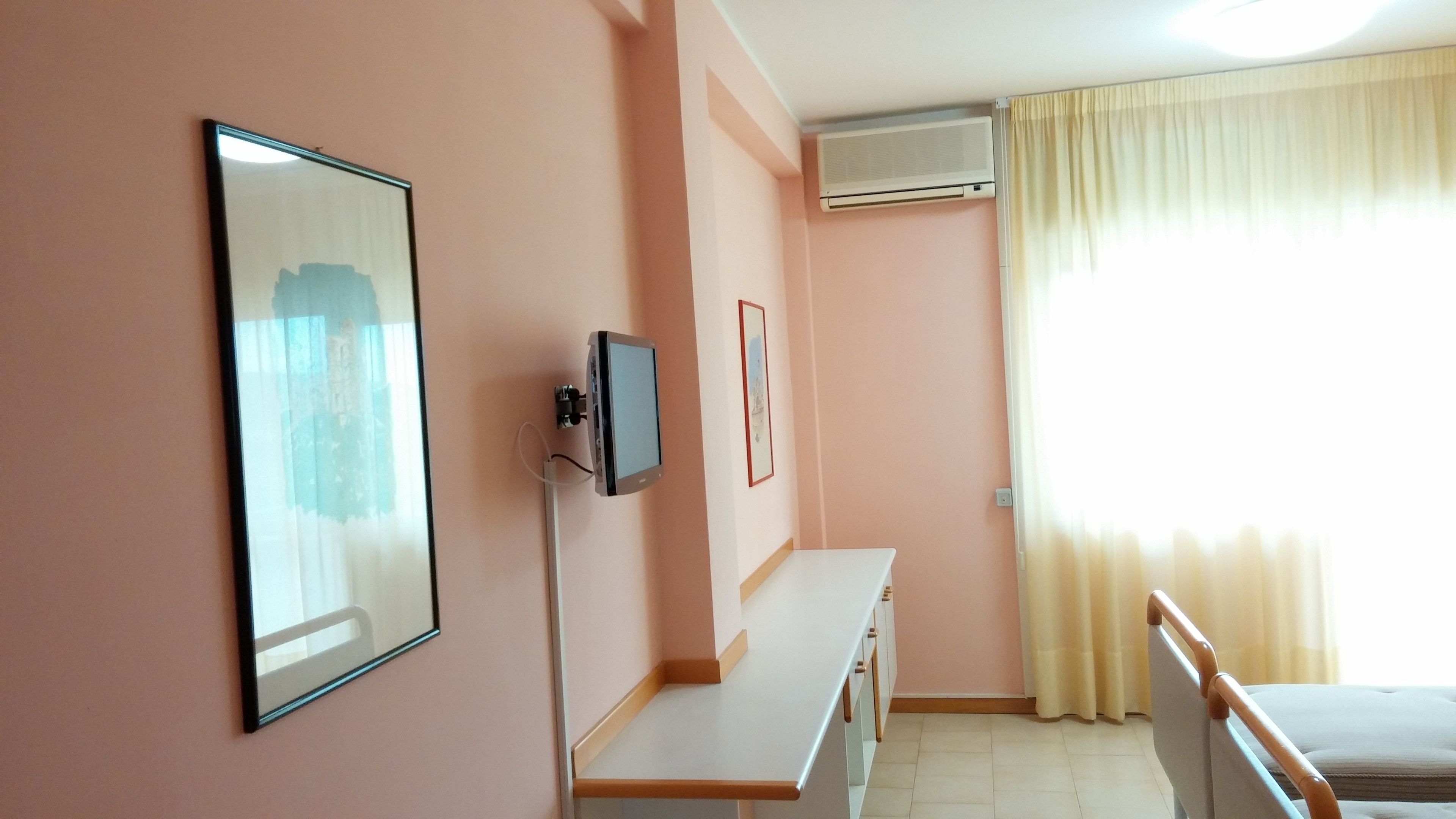 Ein Hotelzimmer mit Bett, Schreibtisch, Fernseher und Klimaanlage.