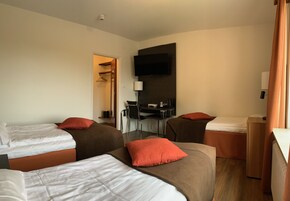 A hotel room with two beds, a desk, and a TV.