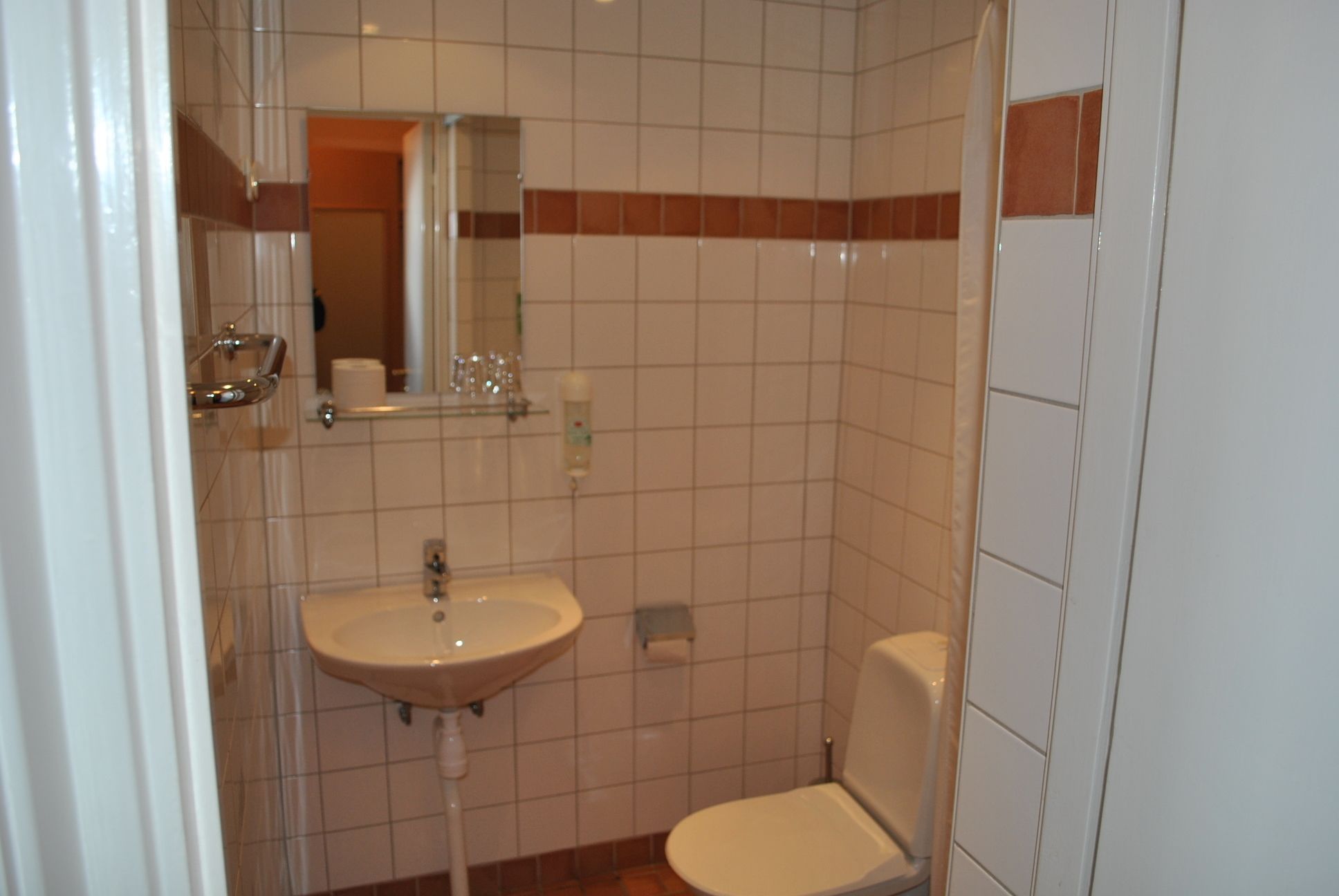 Ein kleines Badezimmer mit Waschbecken, Spiegel und Toilette.