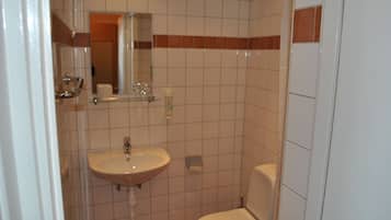 Ein kleines Badezimmer mit Waschbecken, Spiegel und Toilette.