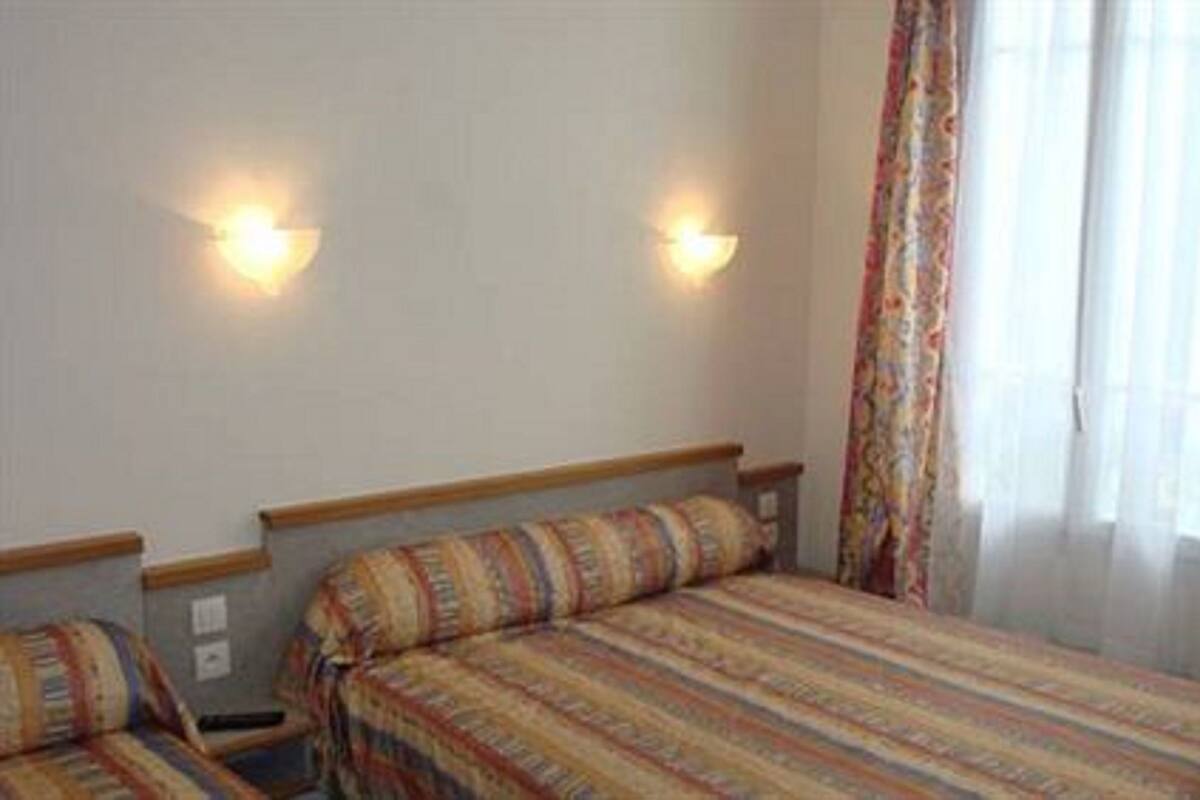 Una habitación de hotel con dos camas, un ventanal con cortinas e iluminación en la pared.