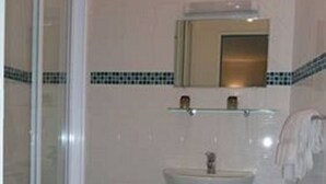A bathroom with a glass shower enclosure, a pedestal sink, and a mirror above it. - Hotel Des Vosges (Paris)