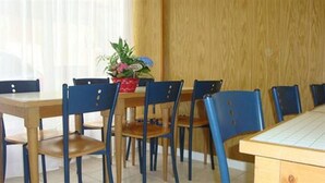 A dining area with wooden tables and blue chairs. - Hotel Des Vosges (Paris)