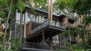 A modern multi-story building with balconies, surrounded by dense forest. - Plataran Puncak Residences (Cisarua)