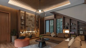 A modern living room with a wooden ceiling, a stone wall, and a large window. - Plataran Puncak Residences (Cisarua)