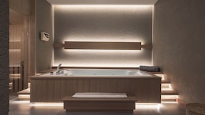 A modern bathroom with a freestanding bathtub, wooden paneling, and a wall-mounted light fixture. - Plataran Puncak Residences (Cisarua)
