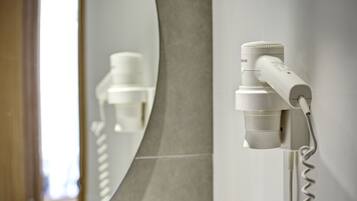 A hair dryer mounted on a wall with a mirror reflecting it.