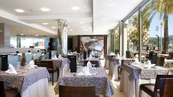Um restaurante com mesas postas para refeições, uma grande janela com vista e um design de interiores moderno.