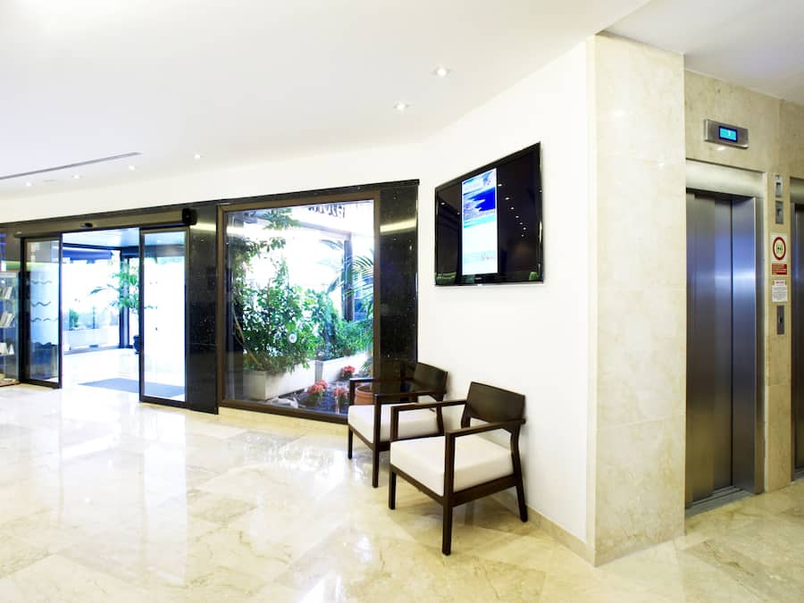 Un vestíbulo de hotel con mostrador de recepción, zona de estar y ascensores.