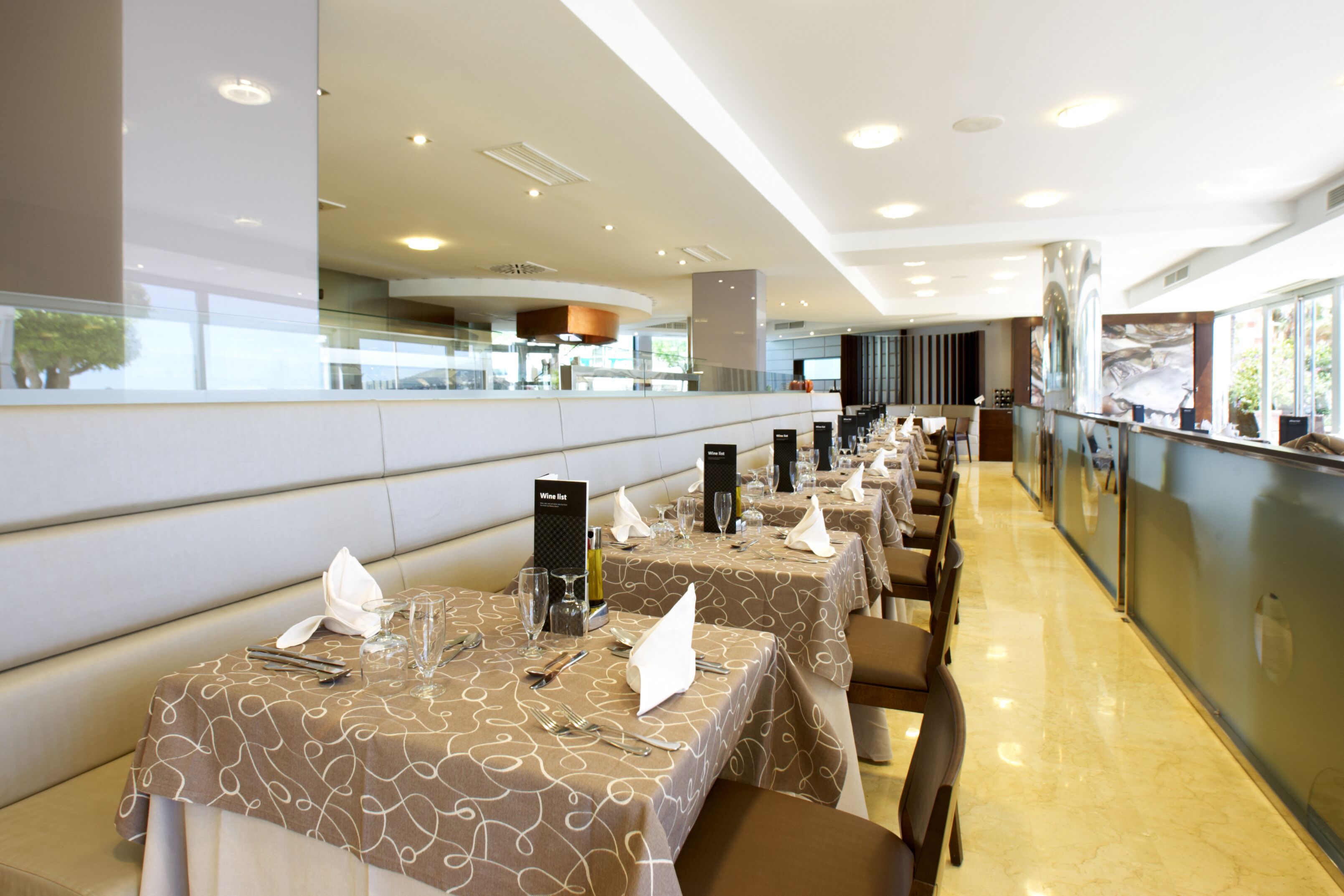 Un restaurante con varias mesas, cada una dispuesta con cubiertos, vasos y servilletas.