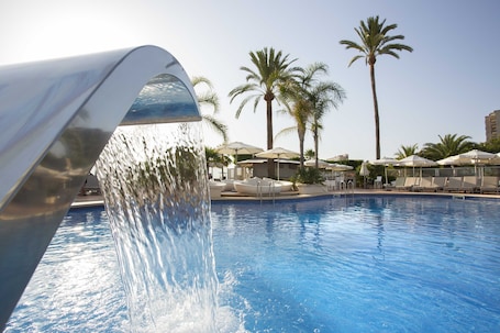 Una piscina al aire libre, sillones reclinables de piscina