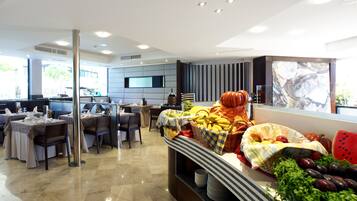 Un comedor moderno con una mesa de buffet, disposición de asientos y una pantalla de televisión.