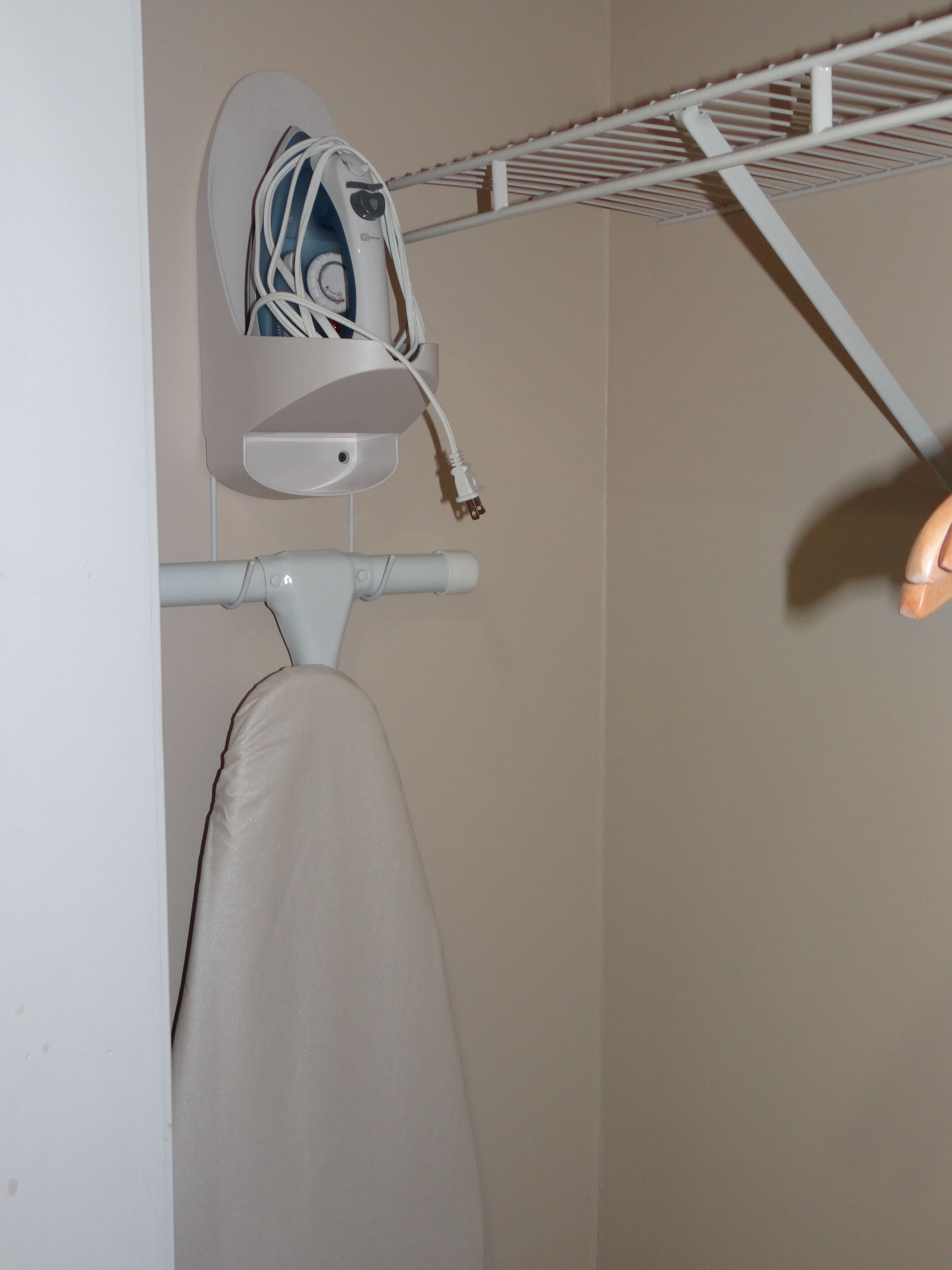 Eine weiße Wand mit einem weißen Regal, auf dem ein weißes Gerät und ein weißes Kabel liegen.