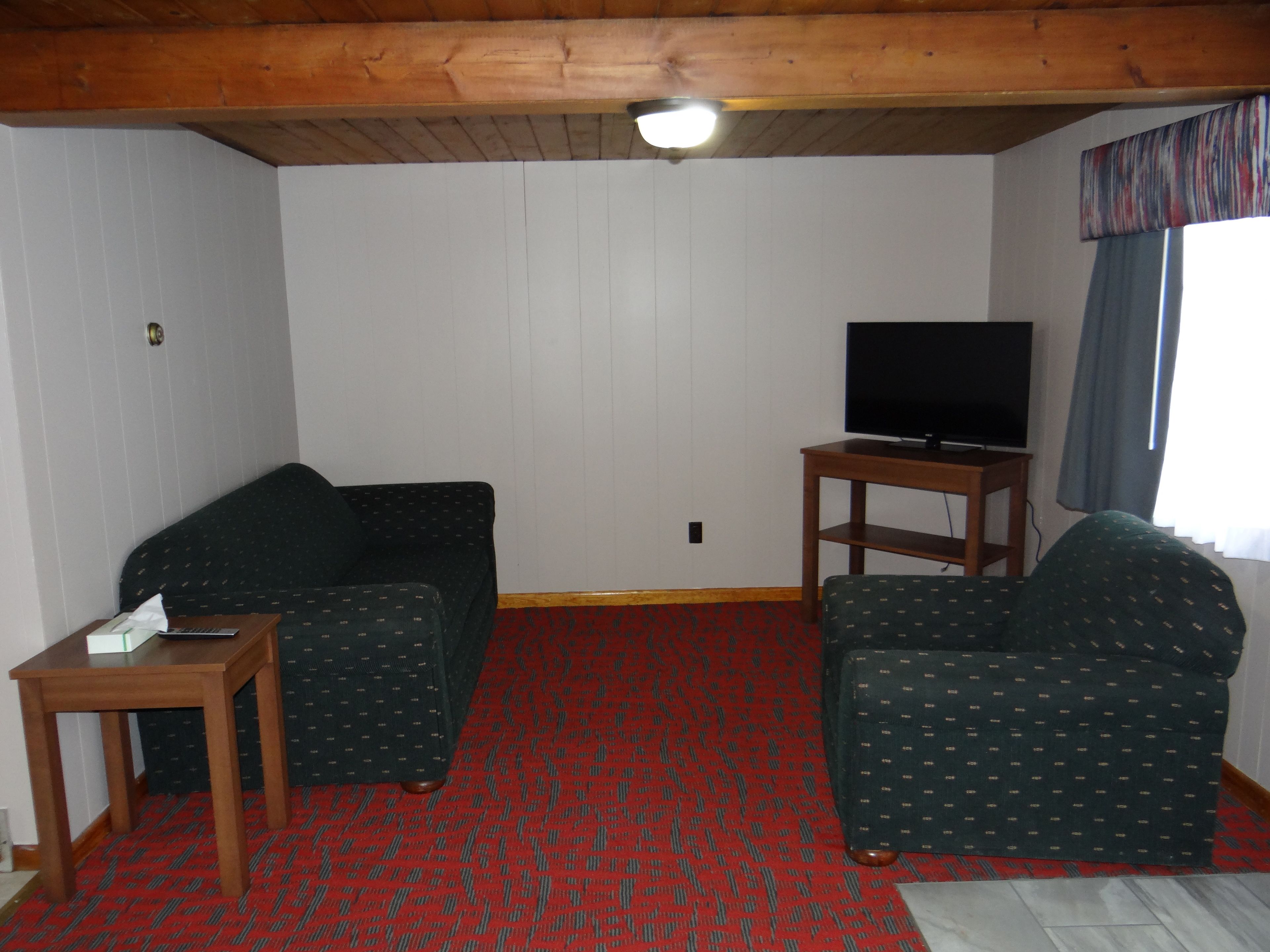 A living room with a sofa, a chair, a small table, and a TV on a stand.